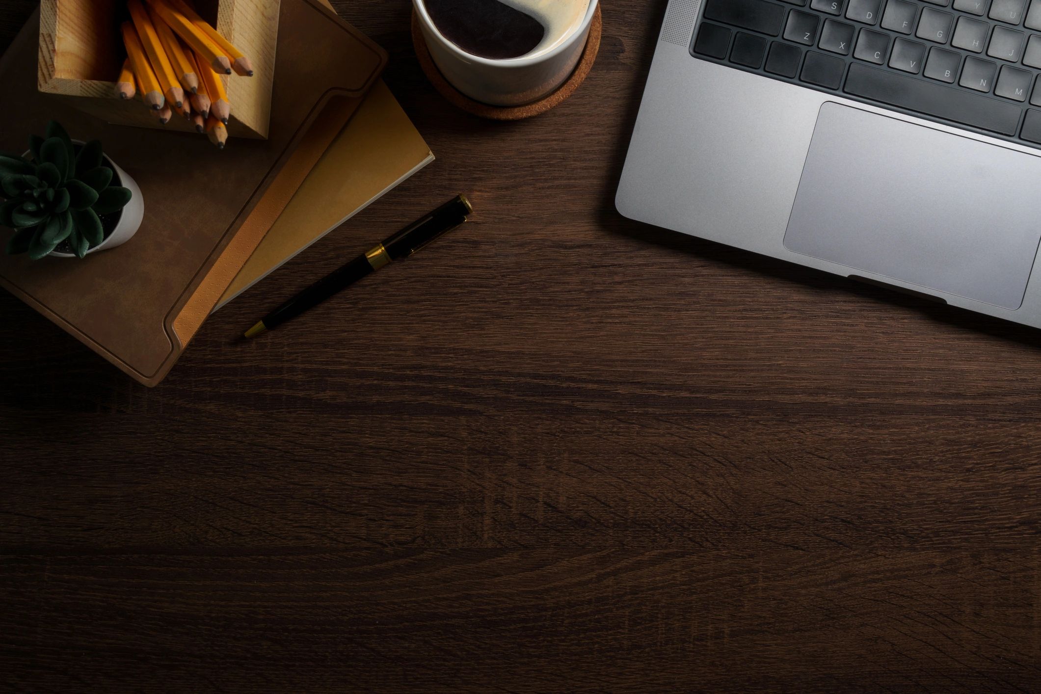 Top view of a laptop and coffee on a wooden desk, representing online work